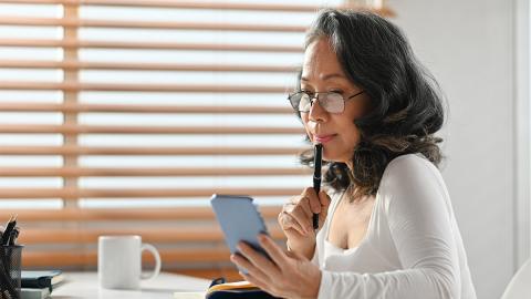 Frau mit Brille schaut auf Smartphone