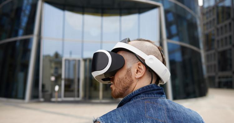 Mann mit VR Brille vor Glasgebäude