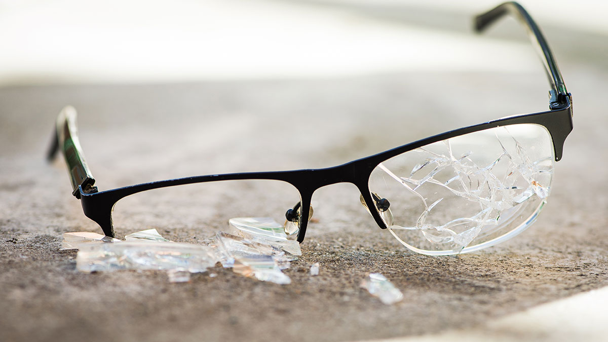 Brille mit zerbrochenen Gläsern auf Steinboden