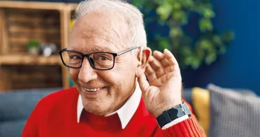 älterer Mann hält sich die Hand ans Ohr