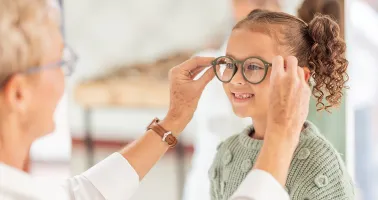 Frau setzt Kind Brille auf