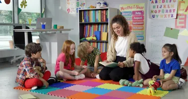 Frau sitzt mit Gruppe Kinder zusammen