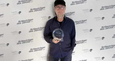 Mann mit Basecap und Brille hält eine Auszeichnung in der Hand