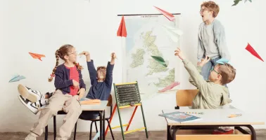 Kinder lassen in der Klasse Papierflieger fliegen