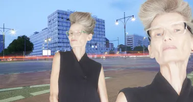 ältere Dame mit markanter Brille und Frisur steht in Berlin auf der Straße