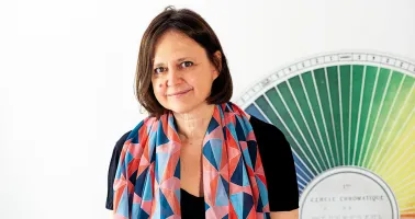 Dame mit buntem Schals steht vor Farbpalette