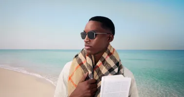 Mann mit Sonnenbrille und Schal am Strand