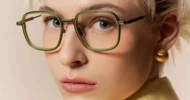 blonde Frau schaut durch grüne Brillenfassung