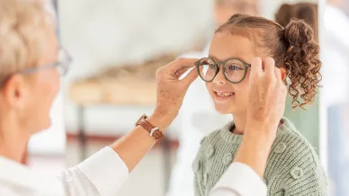 Frau setzt Kind Brille auf