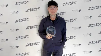 Mann mit Basecap und Brille hält eine Auszeichnung in der Hand