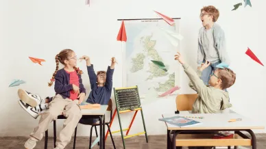 Kinder lassen in der Klasse Papierflieger fliegen