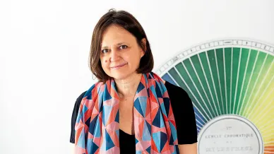 Dame mit buntem Schals steht vor Farbpalette