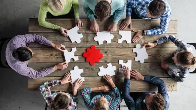 Mehrere Personen mit Puzzle am Tisch