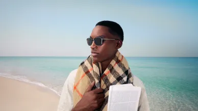 Mann mit Sonnenbrille und Schal am Strand