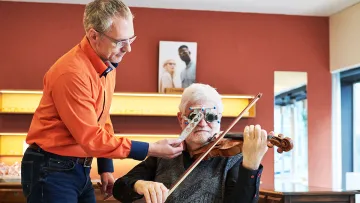 Optiker mit Kunde an der Geige