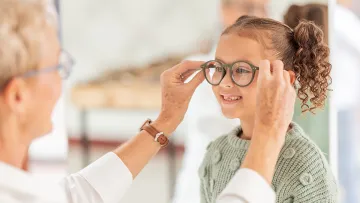 Frau setzt Kind Brille auf