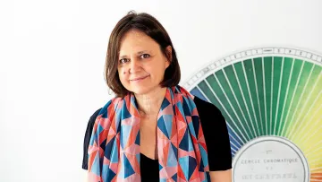 Dame mit buntem Schals steht vor Farbpalette