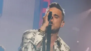 Robbie Williams singt in ein Mikrofon