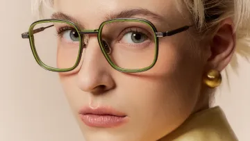 blonde Frau schaut durch grüne Brillenfassung