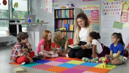 Frau sitzt mit Gruppe Kinder zusammen