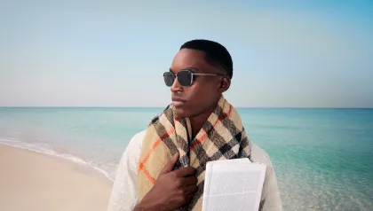 Mann mit Sonnenbrille und Schal am Strand