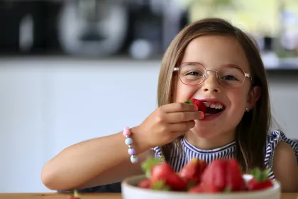 Mädchen mit Brille isst Erdbeeren