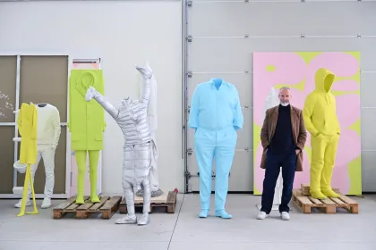 Erwin Wurm inmitten seiner Kunstwerke stehend