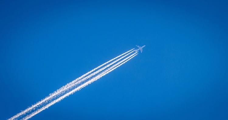 Flugzeug mit Kondensstreifen am Himmel.