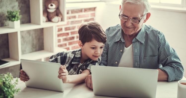Opa und Enkelkind sitzen am Laptop