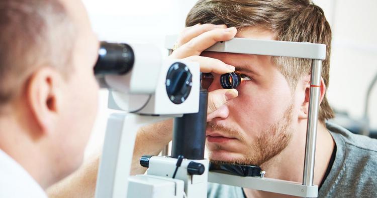 Optometrist macht Spaltlampenuntersuchung von Netzhaut 