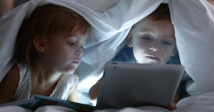 Kinder unter Bettdecke mit Tablet