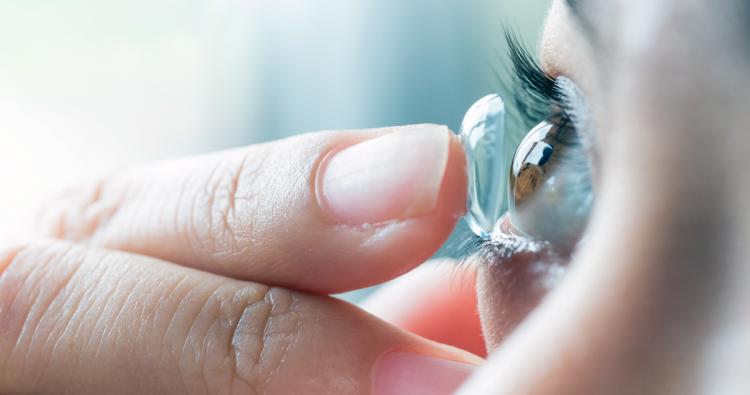 Eine Frau setzt sich eine Kontaktlinse ein.