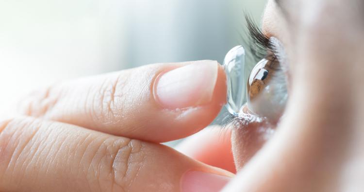 Eine Frau setzt sich eine weiche Kontaktlinse ein