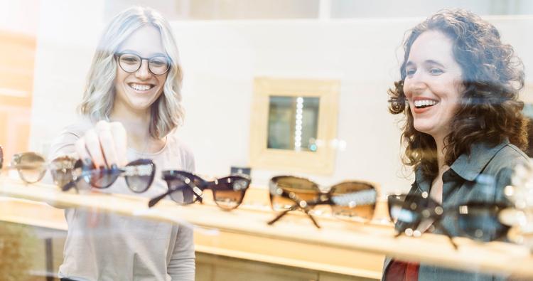 Zwei Damen betrachten verschiedene Brillenmodelle