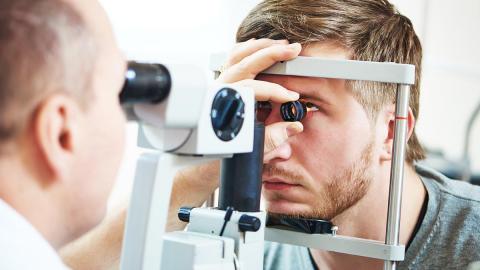 Optometrist macht Spaltlampenuntersuchung von Netzhaut 