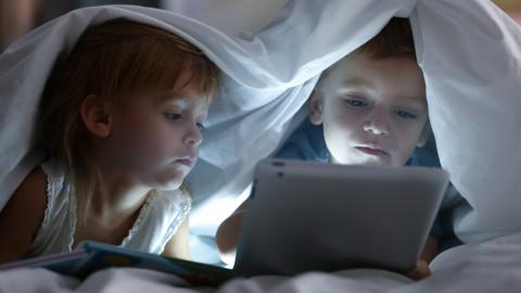 Kinder unter Bettdecke mit Tablet