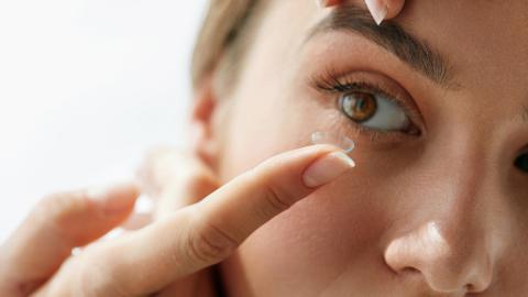 Eine junge Frau mit einer Kontaktlinse auf dem Finger in einer Close-Up-Aufnahme