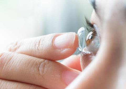 Eine Frau setzt sich eine weiche Kontaktlinse ein