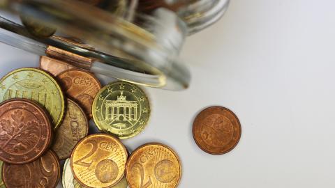 Euromünzen, die aus einem Glas fallen
