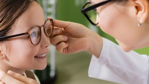 Augenoptikerin testet Sitz der Brille auf der Nase eines Kindes