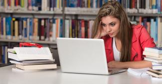 Junge Frau lernt in einer Bibliothek mit ihrem Laptop