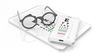 Brille liegt auf Handy und Tablet