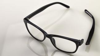 schwarze Brille spiegelt sich auf glatter Oberfläche