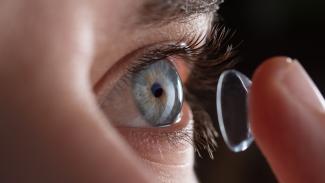 Mensch setzt Kontaktlinse auf Auge