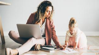 Mutter arbeitet am Laptop und betreut ihre Tochter