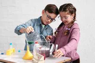 Junge und Mädchen mit Brille experimentieren mit Flüssigkeiten