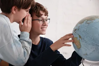 Zwei Jungen schauen zusammen auf einen Globus