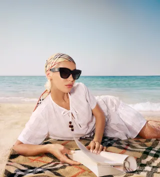 Frau mit Sonnenbrille am Strand liegend