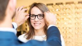 Augenoptiker passt eine Brille bei einer Kundin an